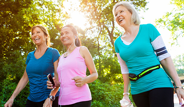 Three women in bright activewear walk together for exercise