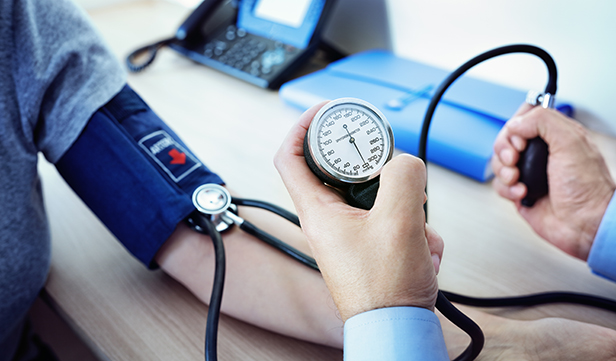 Health care provider uses blood pressure cuff to check patient’s blood pressure