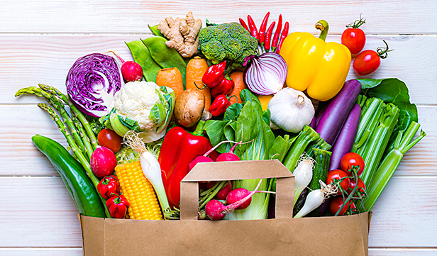 Paper shopping bag filled with rainbow of colorful foods