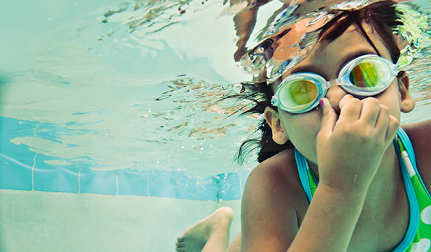 Young girl swimming underwater wearing goggles