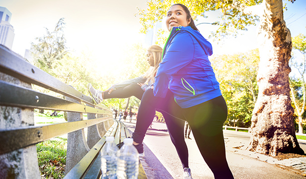 Two women stretch in a park before a run